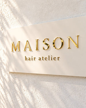 【AI制作イメージ】明るい白い壁と自然光のMAISON hair atelier｜ミラーゴールド立体切り文字ロゴサイン